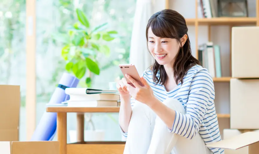 部屋でスマホを操作する女性