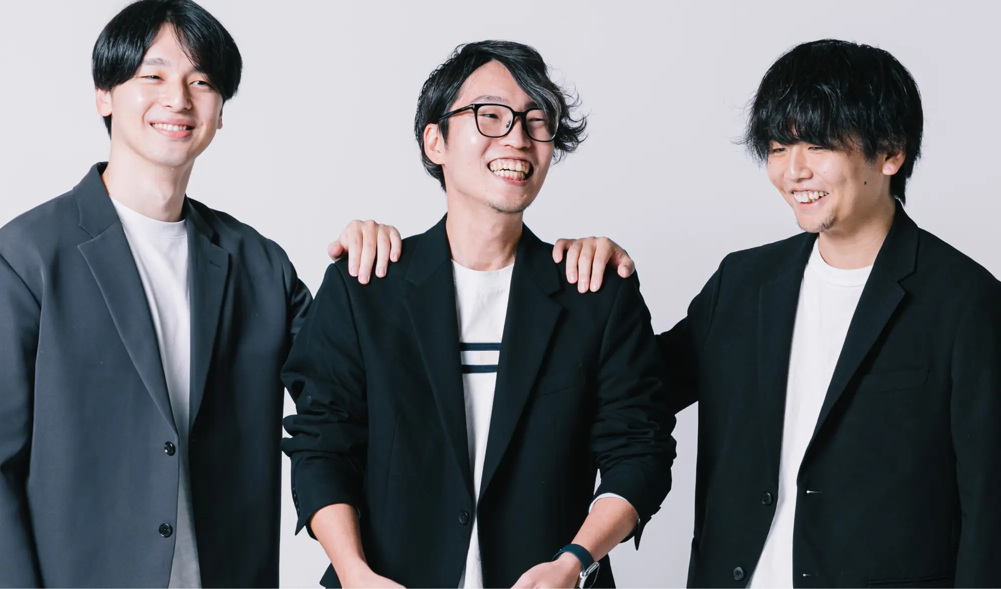 笑顔で肩を組む3人の男性